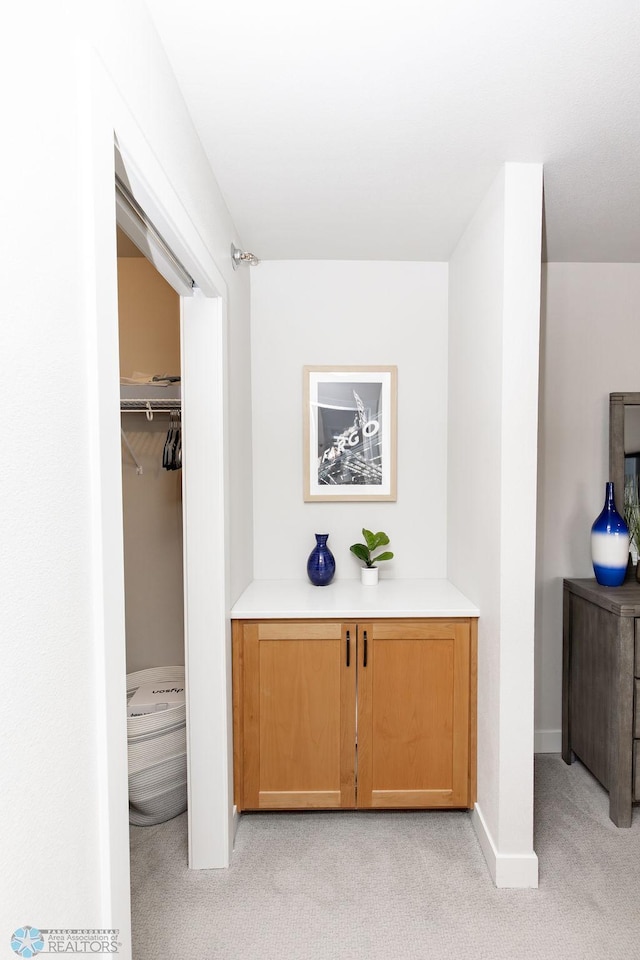 hall with light colored carpet and baseboards