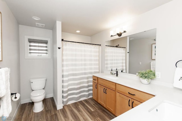 bathroom with vanity, toilet, baseboards, wood finished floors, and visible vents