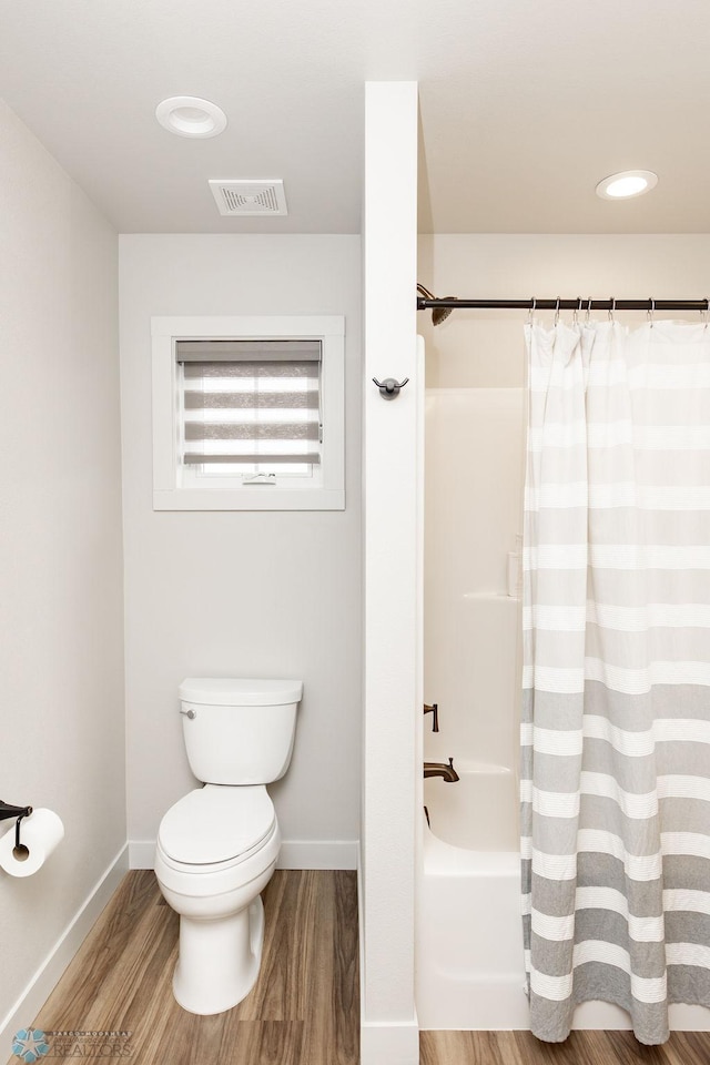 full bath featuring baseboards, shower / bath combo, toilet, and wood finished floors