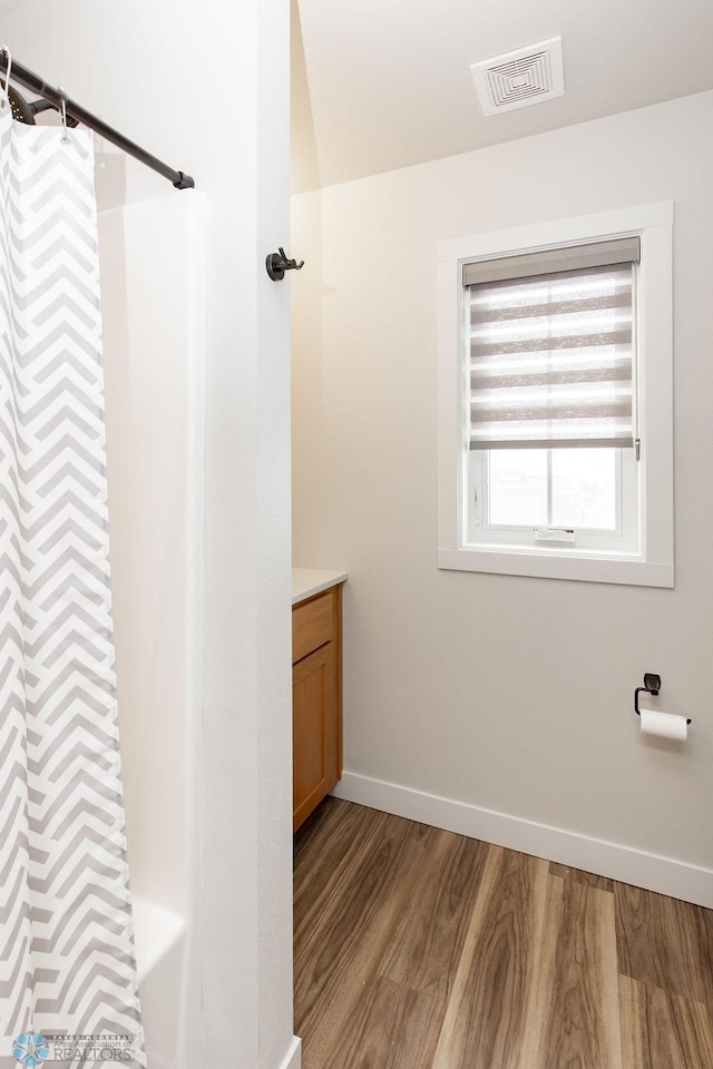 full bath with visible vents, vanity, wood finished floors, curtained shower, and baseboards