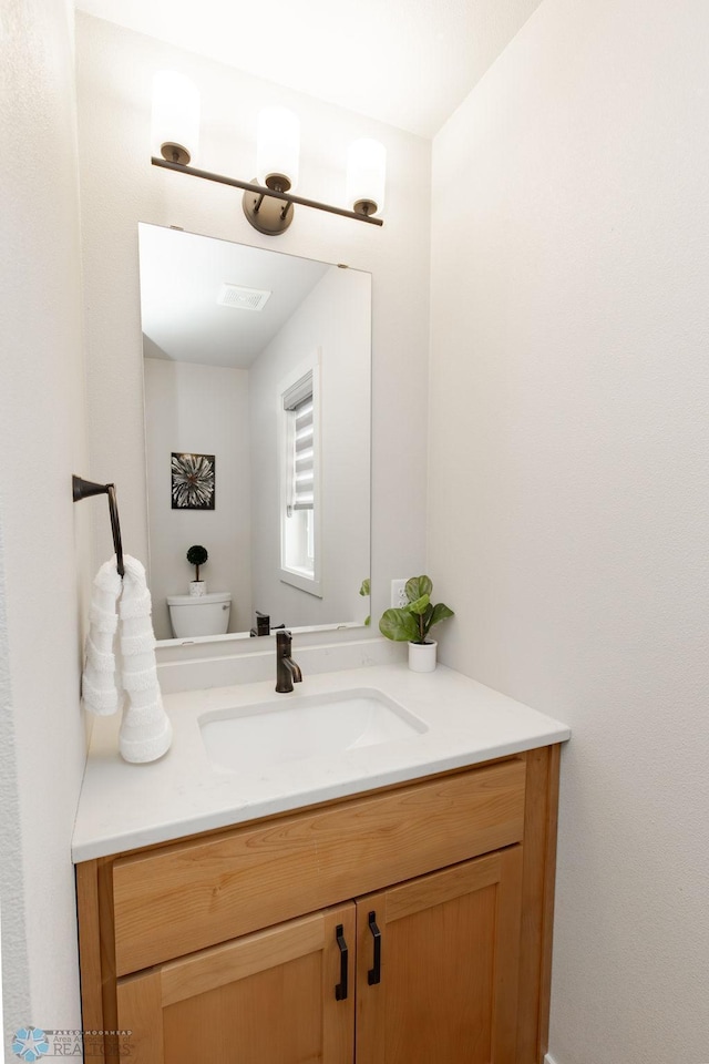 bathroom featuring vanity, toilet, and visible vents