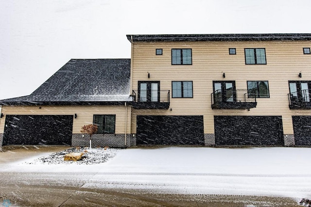 snow covered property with a garage and concrete driveway