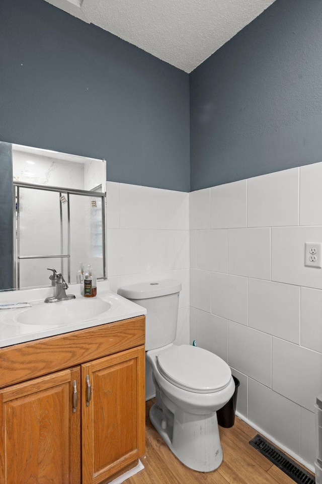 bathroom featuring vanity, wood finished floors, a shower stall, and toilet