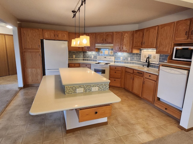 2155 6th Ln SE Unit 301, Cambridge, MN 55008 - kitchen with white appliances, under cabinet range hood, backsplash, light countertops, and brown cabinets