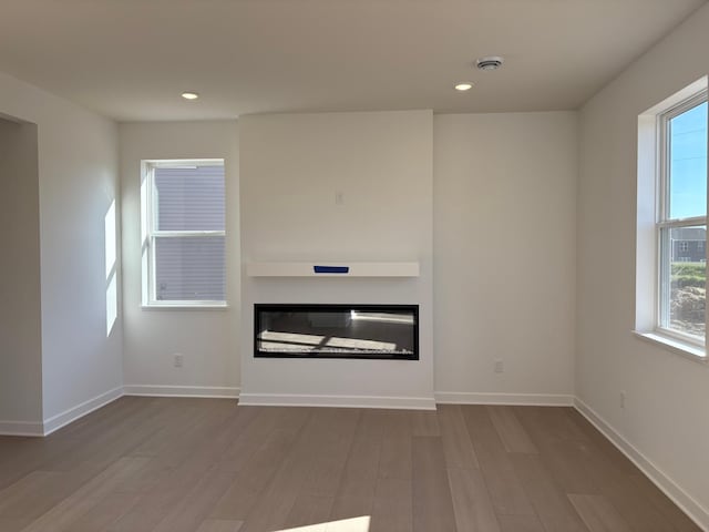 22648 Isla Way, Rogers, MN 55374 - unfurnished living room featuring a glass covered fireplace, wood finished floors, healthy amount of natural light, and recessed lighting