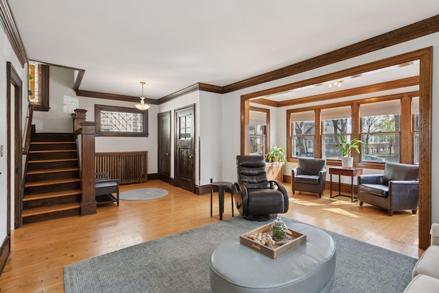 living area with wood-type flooring, baseboards, ornamental molding, and stairway