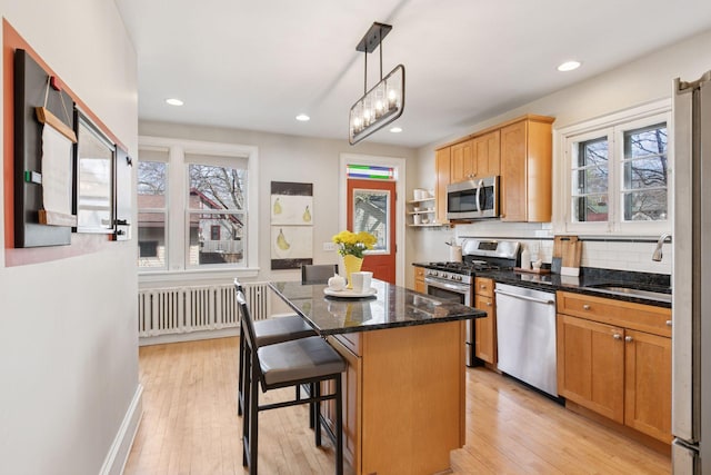 kitchen featuring plenty of natural light, a center island, a sink, radiator, and stainless steel appliances