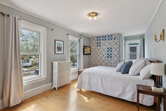 bedroom featuring crown molding, a textured ceiling, radiator, and hardwood / wood-style floors