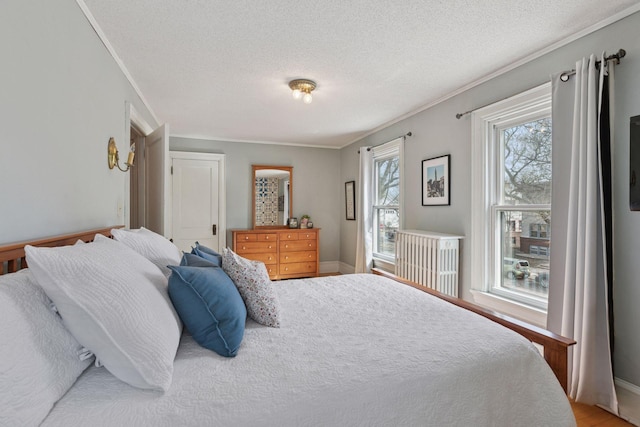 bedroom featuring crown molding, a textured ceiling, light wood finished floors, and baseboards