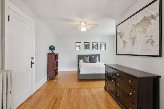 bedroom with baseboards, light wood finished floors, and radiator heating unit