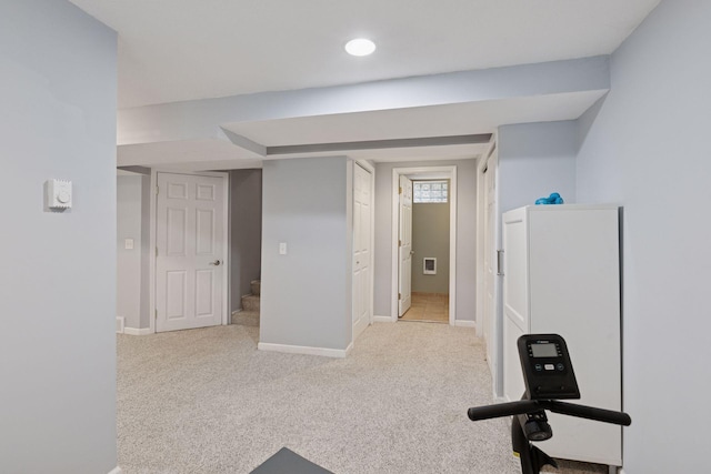 workout area featuring baseboards and light colored carpet