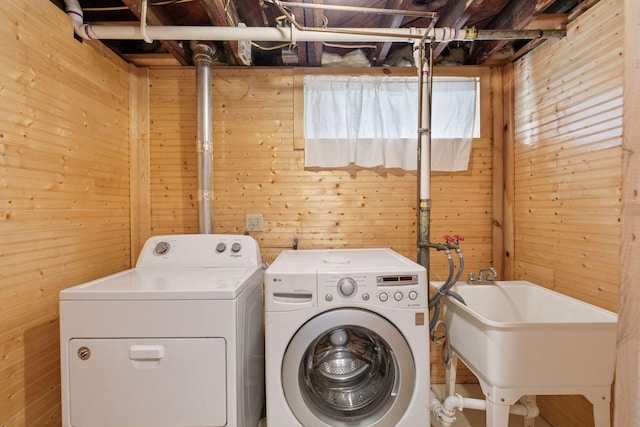 laundry area featuring a sink, washer and dryer, and wooden walls