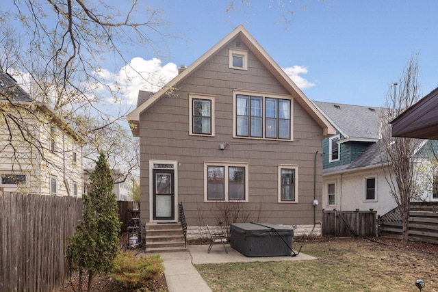 back of property with entry steps, a patio, a hot tub, and a fenced backyard