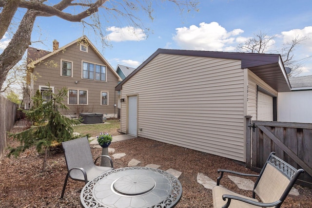 back of house featuring a fenced backyard, a hot tub, and a chimney