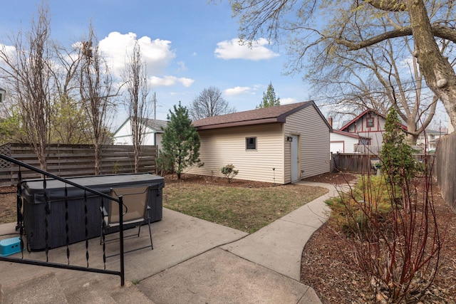 exterior space featuring a patio, a fenced backyard, a hot tub, and an outdoor structure