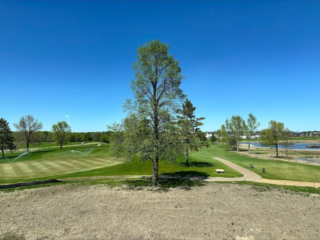 view of property's community with a water view, a lawn, and view of golf course