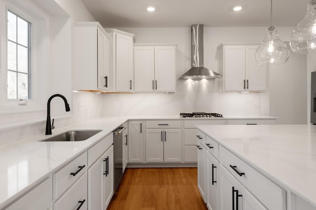 kitchen featuring a sink, wall chimney exhaust hood, dishwasher, white cabinetry, and recessed lighting