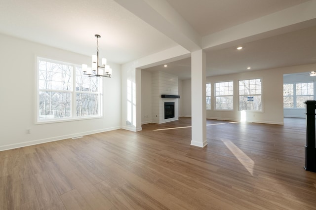 unfurnished living room with a chandelier, wood finished floors, a large fireplace, recessed lighting, and baseboards