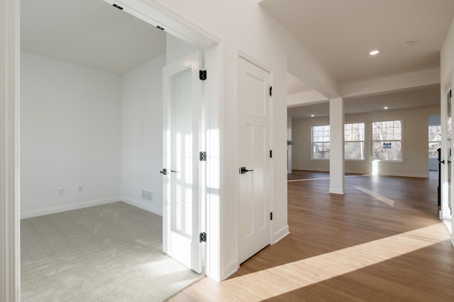 corridor with baseboards, wood finished floors, recessed lighting, and ornate columns
