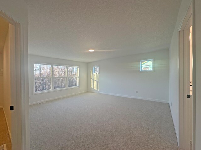 spare room with a textured ceiling, carpet floors, baseboards, and recessed lighting