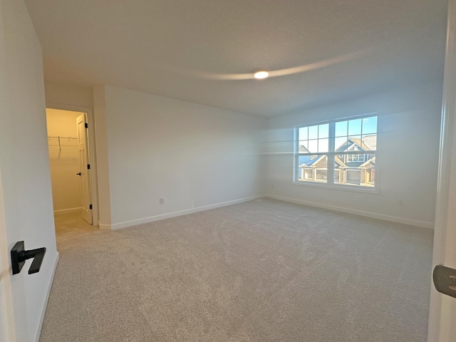 unfurnished room featuring carpet floors and baseboards
