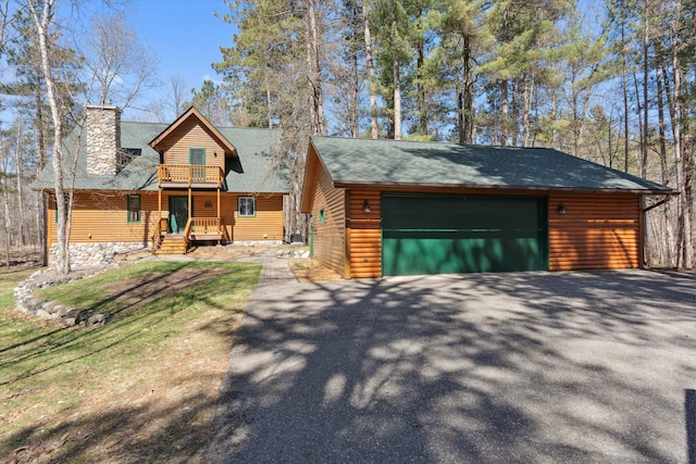 chalet / cabin with a chimney, a balcony, an outbuilding, and faux log siding