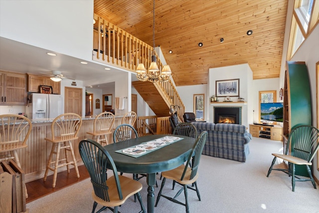 dining area featuring high vaulted ceiling, a warm lit fireplace, wooden ceiling, a chandelier, and recessed lighting