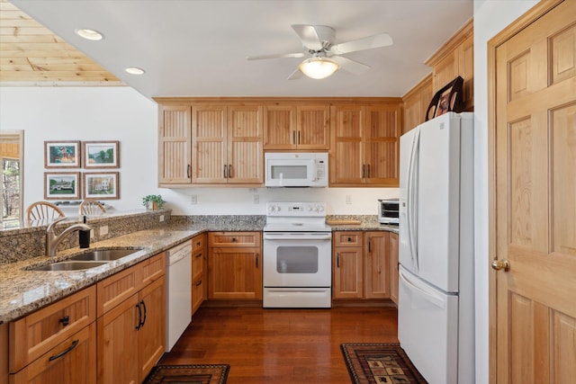 kitchen with white appliances, a sink, dark wood-type flooring, ceiling fan, and light stone counters