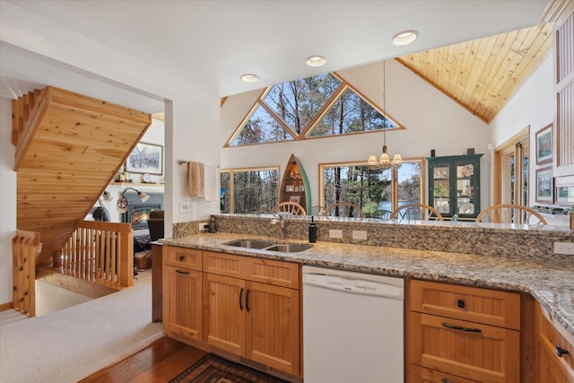 kitchen with white dishwasher, a sink, a chandelier, dark wood-style floors, and light stone counters
