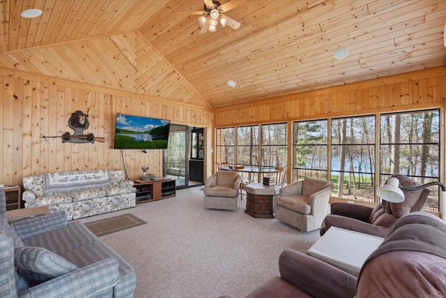 living room with healthy amount of natural light, wooden walls, wooden ceiling, carpet flooring, and a ceiling fan