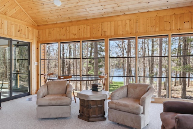 sunroom / solarium with lofted ceiling, wood ceiling, a water view, carpet, and wooden walls