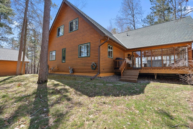 rear view of property with roof with shingles, log veneer siding, a deck, and a lawn