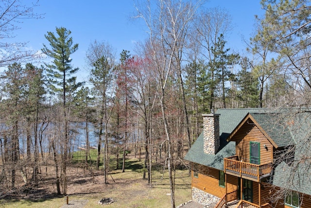 view of property exterior featuring a chimney, a shingled roof, a wooden deck, and log veneer siding