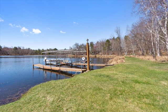 dock area with a water view, a yard, and boat lift