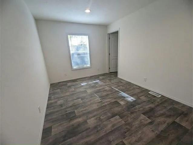 empty room with baseboards, visible vents, and wood finished floors