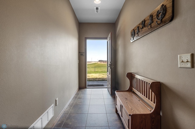 entryway with dark tile patterned floors, baseboards, and visible vents