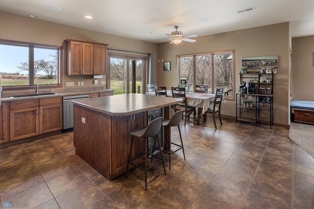 kitchen with visible vents, a center island, brown cabinets, dishwasher, and a sink