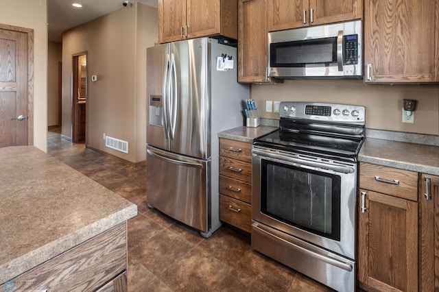 kitchen with dark tile patterned floors, brown cabinetry, visible vents, appliances with stainless steel finishes, and recessed lighting