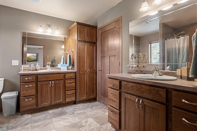 bathroom with toilet, two vanities, and a sink