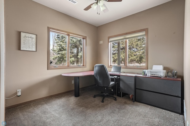 carpeted office space featuring baseboards, ceiling fan, a wealth of natural light, and visible vents