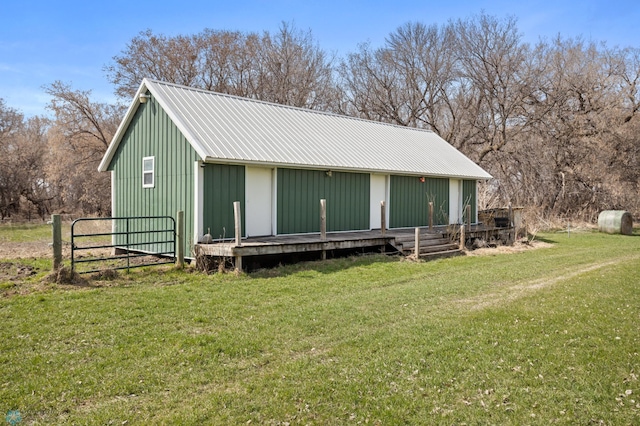 rear view of property with a lawn, board and batten siding, fence, and metal roof