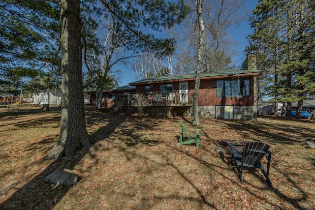 back of property with a deck, a chimney, and a lawn