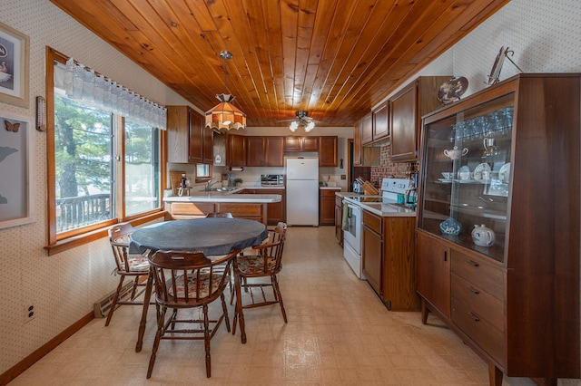 kitchen featuring a sink, wallpapered walls, light floors, white appliances, and light countertops