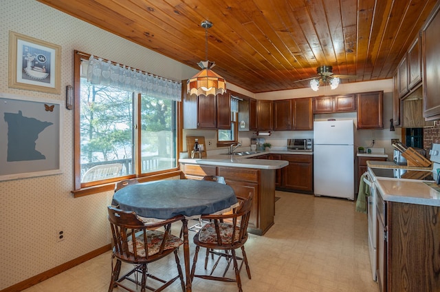 kitchen featuring a sink, a peninsula, white appliances, wooden ceiling, and wallpapered walls