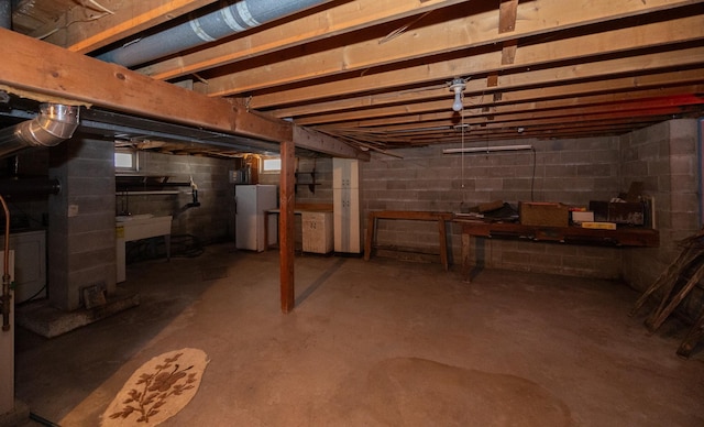 unfinished basement with freestanding refrigerator