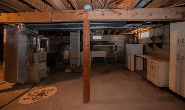 below grade area featuring freestanding refrigerator, water heater, heating unit, and a sink