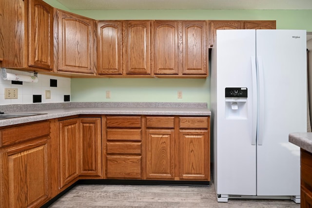 155 Nicholas Dr, Lewiston, MN 55952 - kitchen featuring white fridge with ice dispenser, light wood-style flooring, brown cabinetry, decorative backsplash, and light countertops