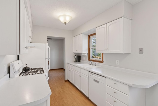 kitchen featuring light wood-style floors, a sink, white cabinetry, and white appliances