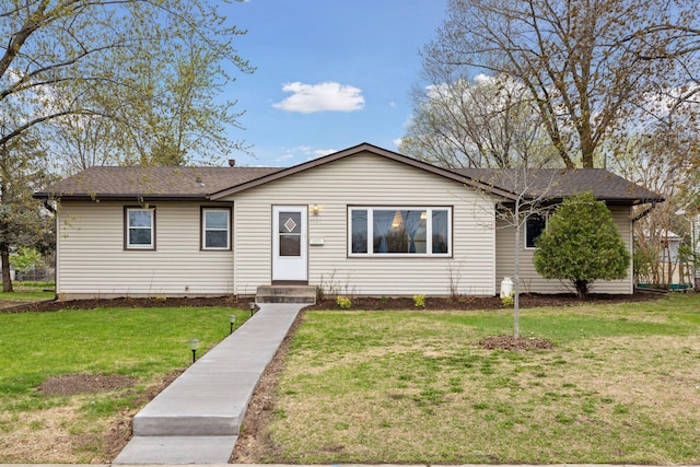 ranch-style house featuring a shingled roof and a front lawn