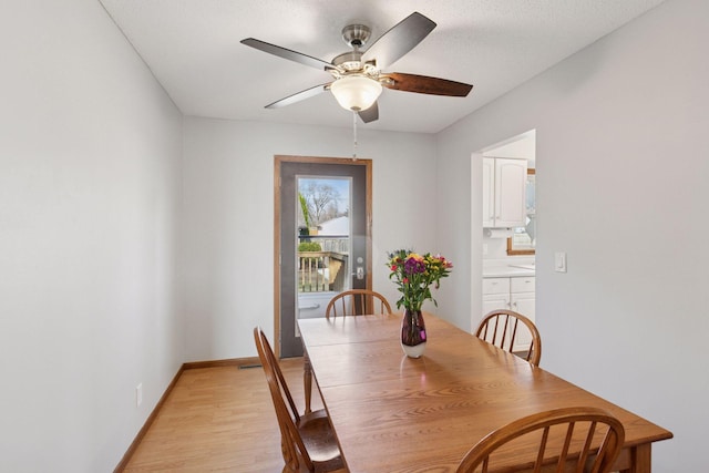 dining room with ceiling fan, baseboards, and light wood-type flooring